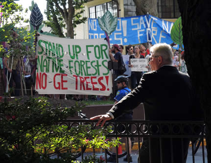 photo of a protest, in the foreground, a man in a suit watches