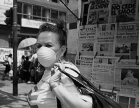 photo of a woman wearing a filter mask on a street corner