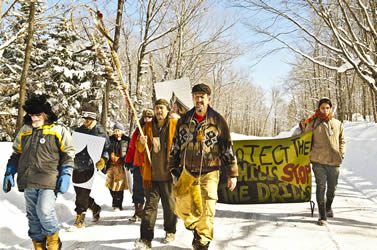 photo of people marching in a demonstration with signs through a snowy forest