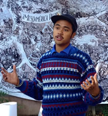 photo of a young man speaking, a fantastic artwork behind him