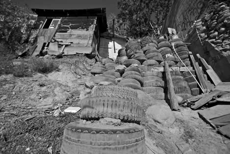 photo of a shack at the top of a hill of tires