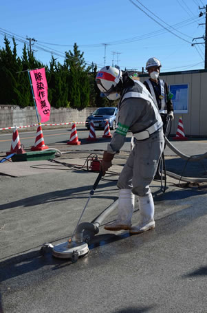 photo of workers wearing protective gear using machinery to clean a flat surface