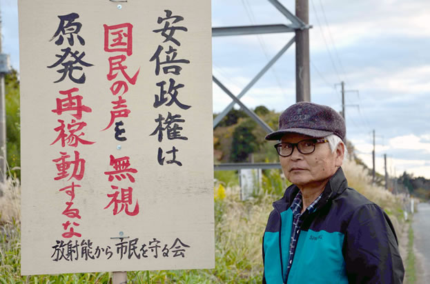 photo of a man standing outside under powerlines, a sign in Japanese hanging near him