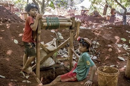 photo of two boys leaning on a winch that descends into a mineshaft