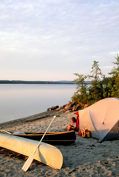 photo of a tent on a beach, canoe and family nearby