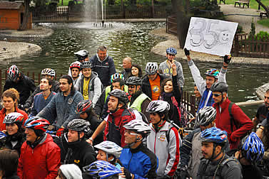 photo of bicycle-helmet wearing demonstrators by a watercourse, one holding a sign that reads: 350