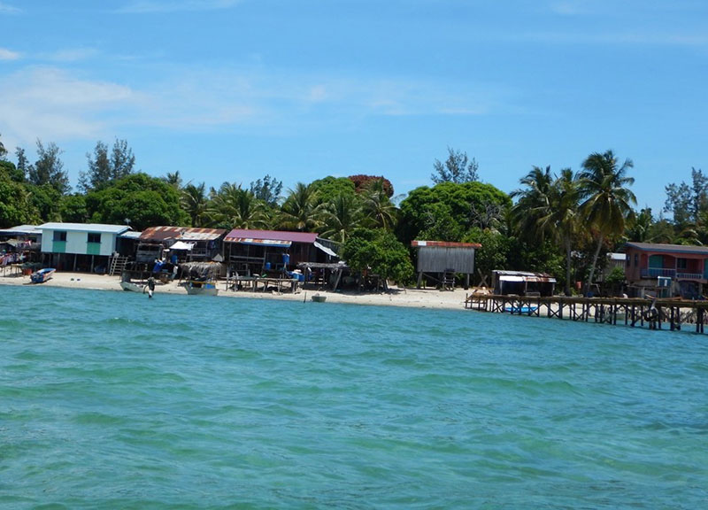 photo of a beach with a village on it, as seen from the sea