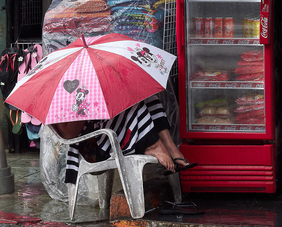 photo of someone hiding under an umbrella in a rainstorm