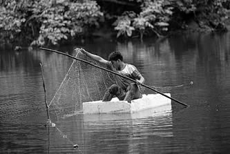 photo of a young man fishing from a raft made of styrofoam packaging