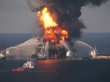 photo of an oil rig burning at sea, surrounded by fireboats spraying water without apparent effect