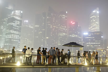 photo of people waiting in a smoky outdoor area, skyscrapers in the background