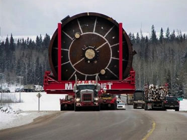 photo of an enormous truck with a gargantuan load driving on a small snowy road