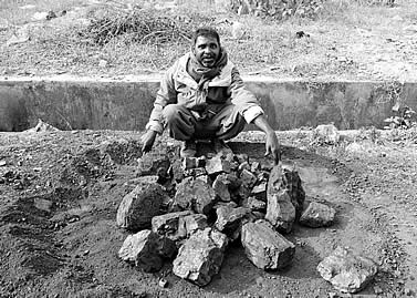 photo of a man by a circle of blocks of coal