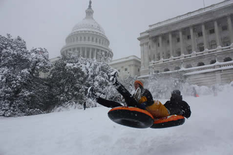 photo of people sledding on an innertube in front of the US capitol