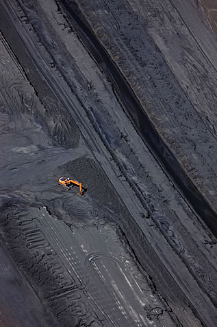 aerial photographic image of dark soil without vegetation, an earthmoving machine small atop it