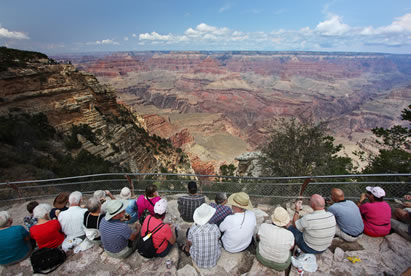 photo of a group of people sitting on the rim of the grand canyon observing