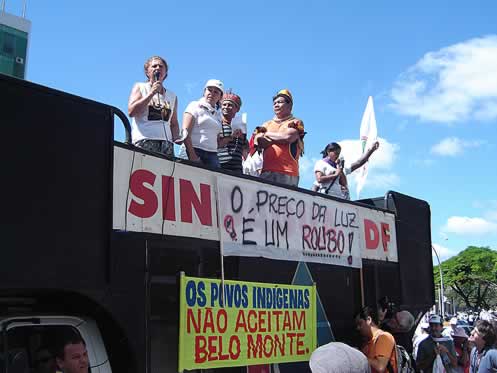 photo of demonstrators on a stage, banners in Portugese