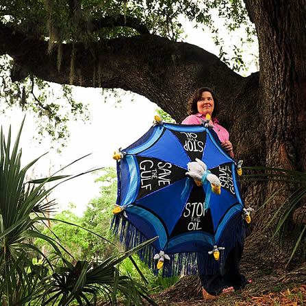 photo of a woman in a cypress woodland, holding an umbrella with 'save the gulf' written on it
