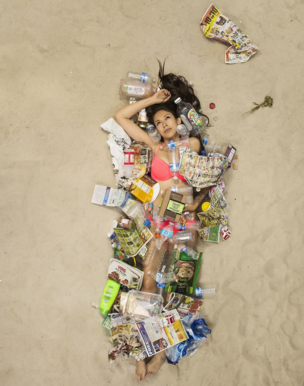 photo of a woman lying on sand, covered in trash