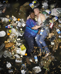 small photo of a couple in a murky puddle full of trash