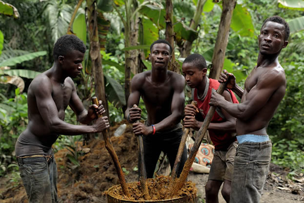 photo of people working together, pounding something to a pulp with poles