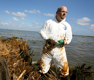 photo of a man in an oily contamination suit on the shore