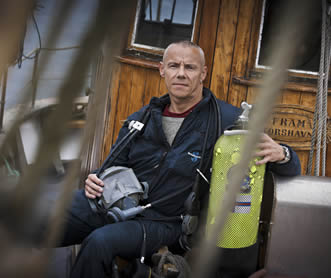 photo of a man sitting on a porch, he is holding a SCUBA tank 