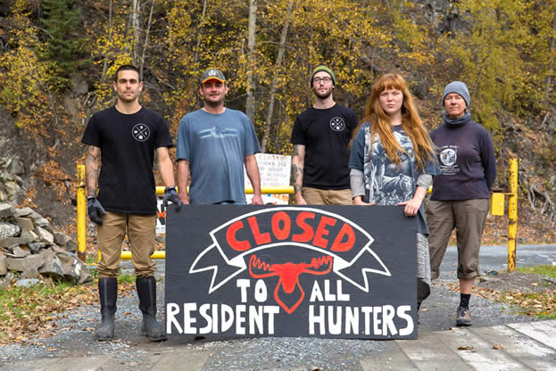 photo of a group blocking a road with a sign that reads, closed to all resident hunters